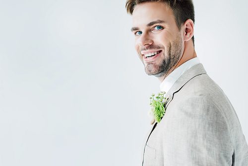 handsome bridegroom in suit with floral boutonniere  isolated on grey