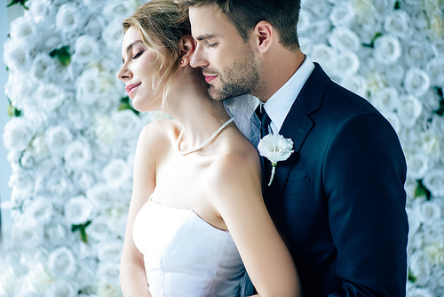 attractive bride and handsome bridegroom hugging with closed eyes