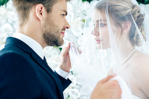 side view of attractive bride and handsome bridegroom looking at each other