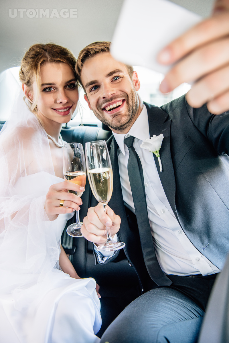 유토이미지 | attractive bride and handsome bridegroom taking selfie in car