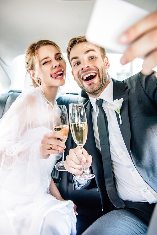 attractive bride and handsome bridegroom taking selfie in car