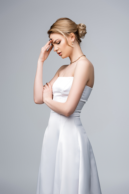 upset woman in wedding dress touching face isolated on grey