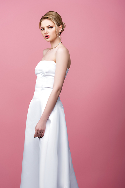 serious bride in white wedding dress  isolated on pink