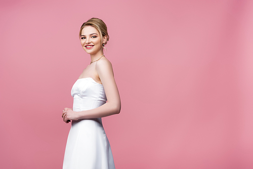 cheerful and young bride in white wedding dress on pink