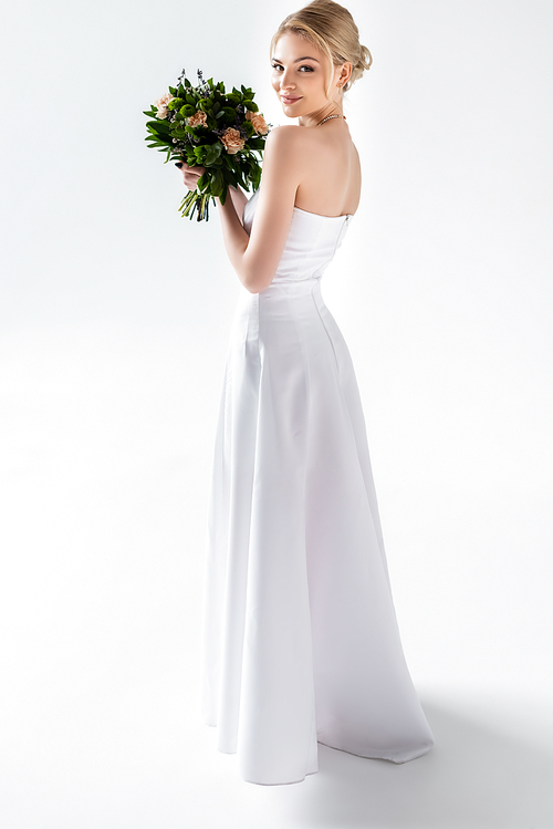 happy bride in elegant wedding dress holding flowers on white