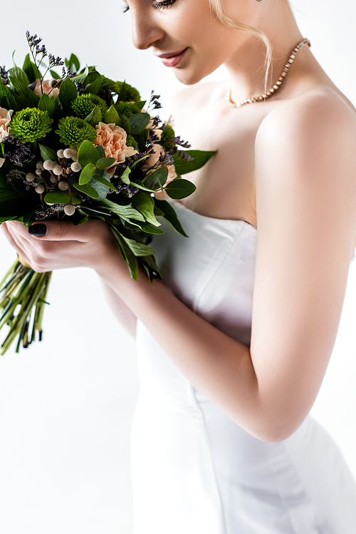 cropped view of bride in elegant wedding dress holding flowers isolated on white