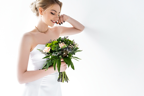 happy young bride in elegant wedding dress holding flowers on white