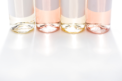 close up view of bottles of white and rose wine with blank labels on white background