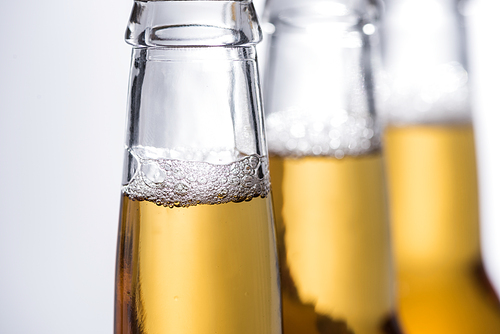 selective focus of beer bottles with bubbles isolated on grey