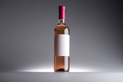 bottle of rose wine and blank label on dark background with back light