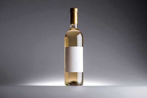 bottle of white wine and blank label on dark background with back light