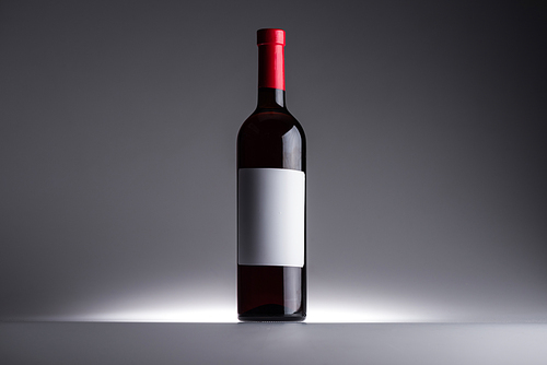 bottle of red wine and blank label on dark background with back light