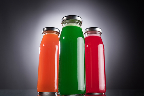 low angle view of glass bottles with colorful liquid on dark background with back light