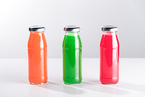 row of glass bottles with multicolored liquid isolated on grey