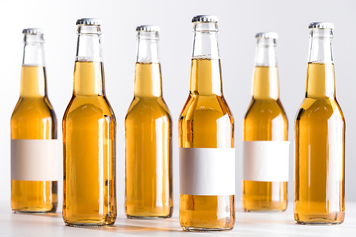 selective focus of beer bottles with blank white labels isolated on grey