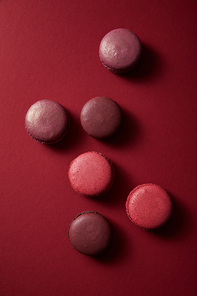 top view of delicious colorful french macaroons on red background