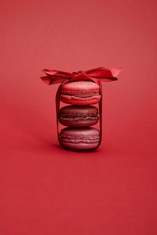 delicious colorful french macaroons wrapped in ribbon with bow on red background