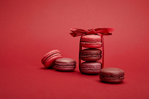 delicious colorful french macaroons wrapped in ribbon with bow on red background