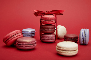 assorted delicious colorful french macaroons with bow on red background