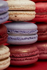 stack of assorted delicious colorful french macaroons on red background