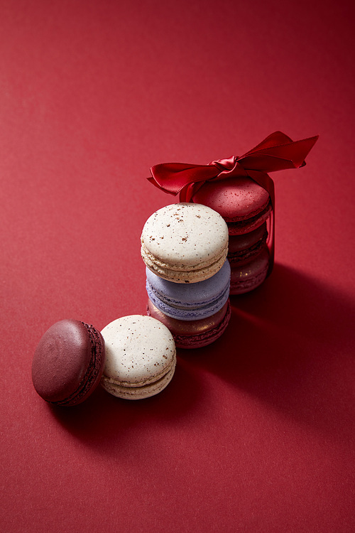 assorted delicious colorful french macaroons with bow on red background