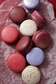 top view of assorted delicious colorful french macaroons on crumpled paper