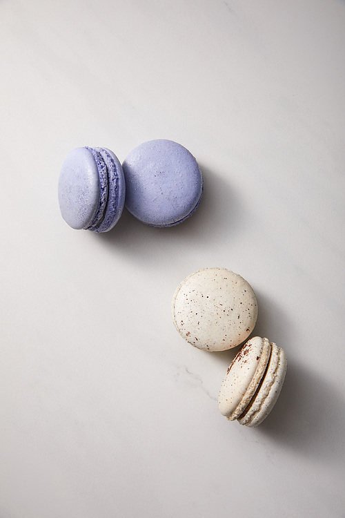 top view of assorted delicious violet and white  french macaroons on grey background