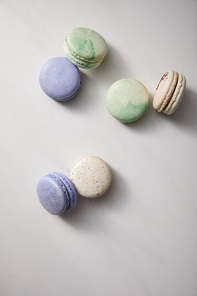 top view of assorted delicious green, violet and white  french macaroons on grey background