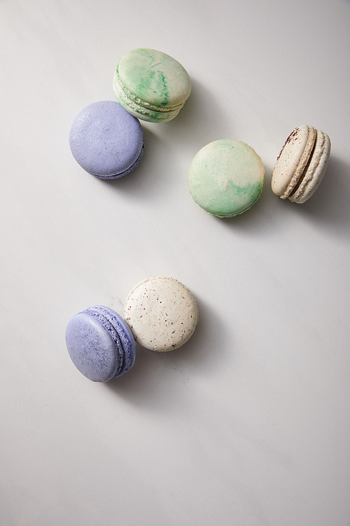 top view of assorted delicious green, violet and white  french macaroons on grey background