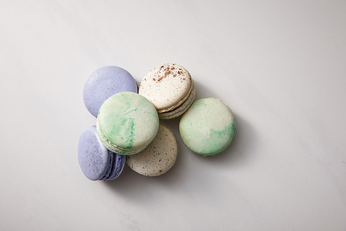 top view of assorted delicious green, violet and white  french macaroons on grey background