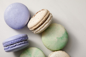 close up view of assorted delicious green, violet and yellow french macaroons on grey background