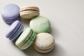 close up view of assorted delicious green, violet and yellow french macaroons on grey background