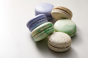 close up view of assorted delicious green, violet and yellow french macaroons on grey background