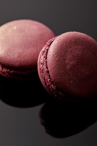 close up view of shiny pink french macaroons on black background