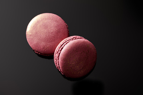 top view of shiny pink french macaroons on black background