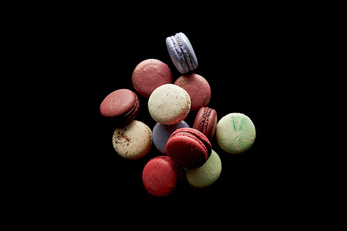 top view of assorted delicious colorful french macaroons isolated on black