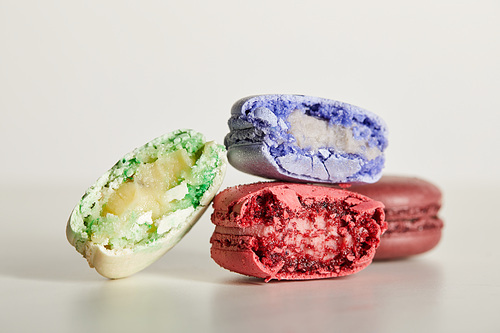 selective focus of assorted delicious bitten colorful french macaroons on white background