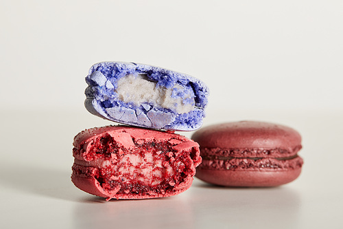 selective focus of assorted delicious bitten colorful french macaroons on white background