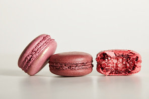 delicious whole and one bitten red french macaroons on white background