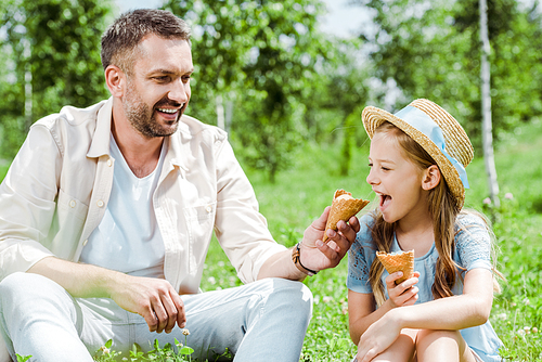 cheerful kid with open mouth near ice cream cone and happy father