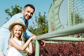 selective focus of cheerful kid in straw hat near happy dad standing in zoo