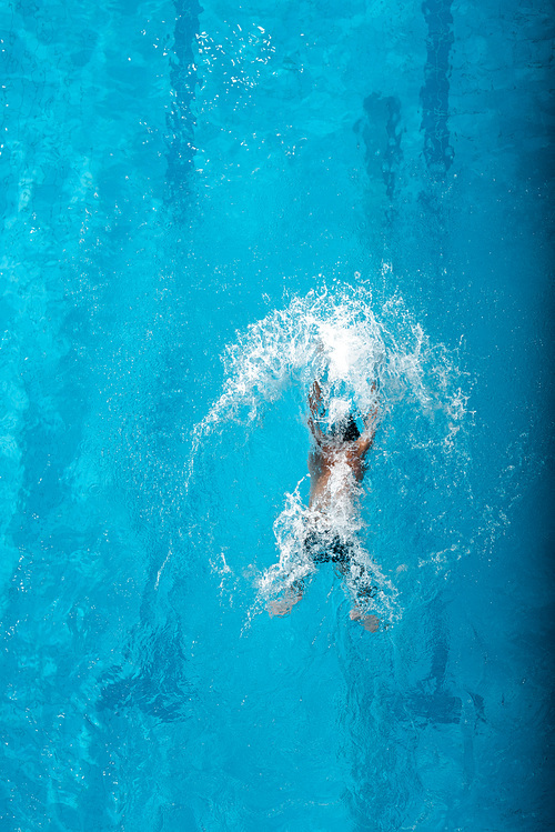 top view of swimmer diving into water in swimming pool