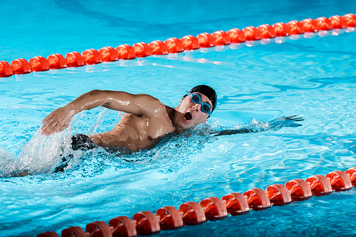 drops of water near swimmer with opened mouth training in swimming pool