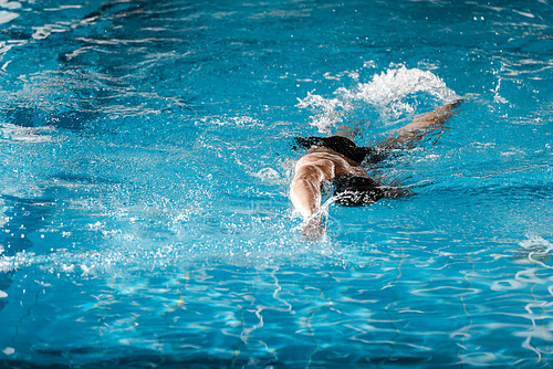athletic man diving in swimming pool with blue water