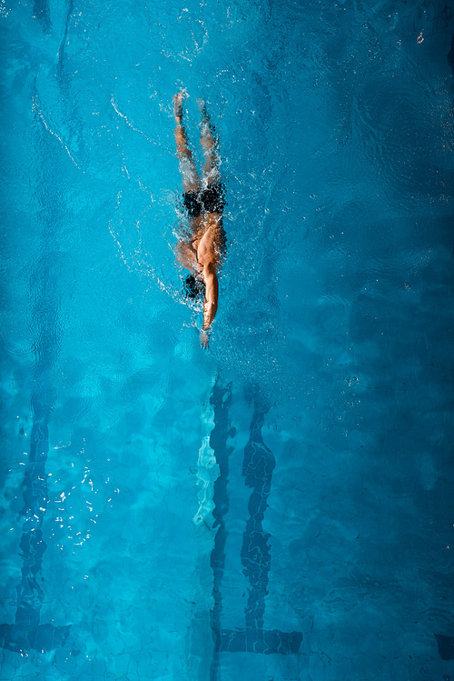 top view of sportsman swimming front crawl in blue water