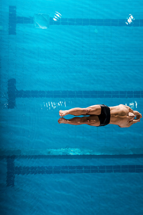 top view of muscular swimmer diving into water