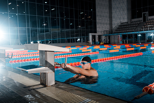 handsome swimmer in goggles exercising in swimming pool