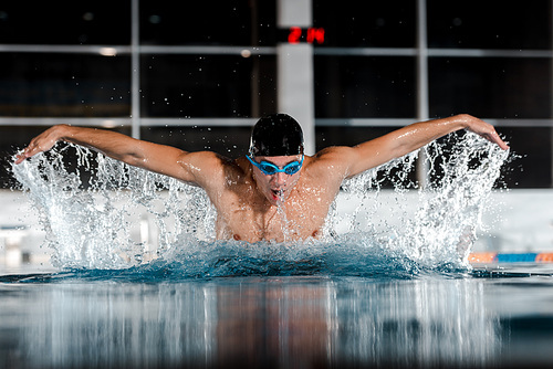 selective focus of sportsman swimming butterfly stroke in swimming pool