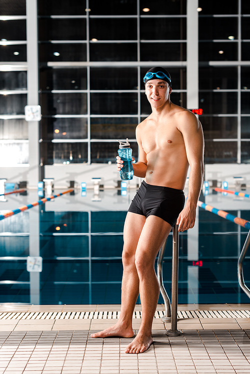 happy swimmer standing and holding sports bottle