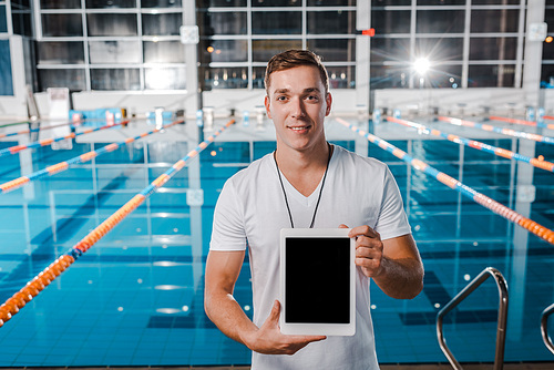 cheerful trainer holding digital tablet with blank screen